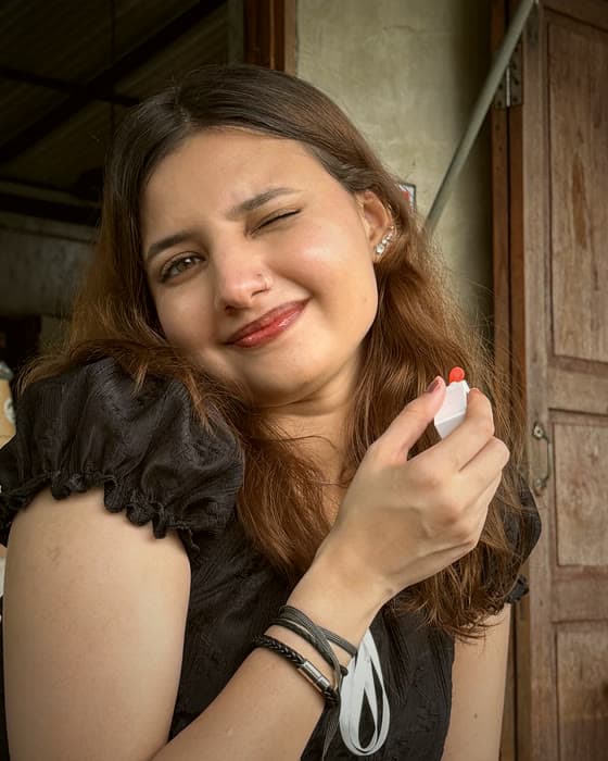Mysbah winking while holding a lip product